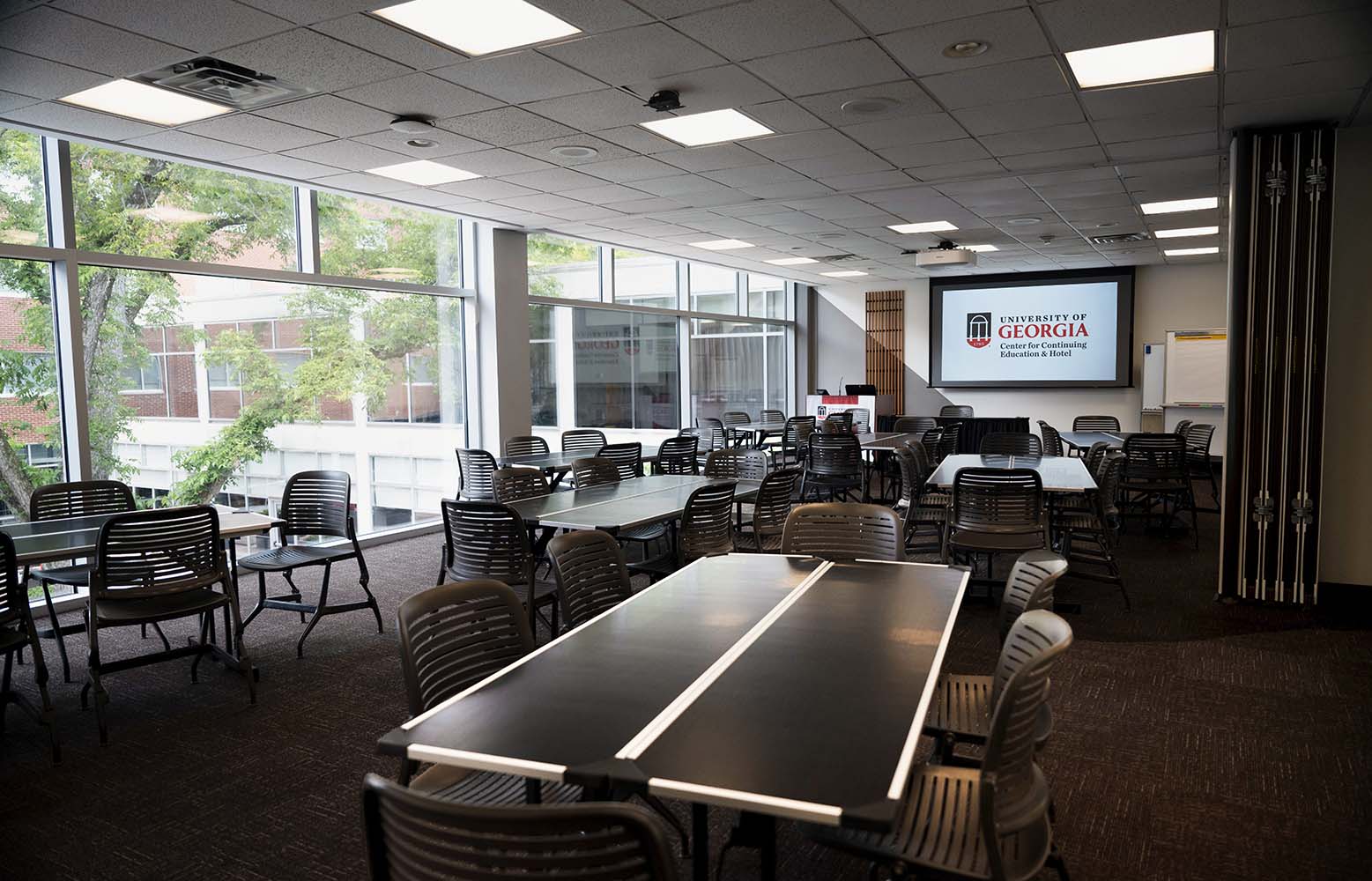 View inside a conference room with tables, chairs, and a podium with a view of the courtyard.