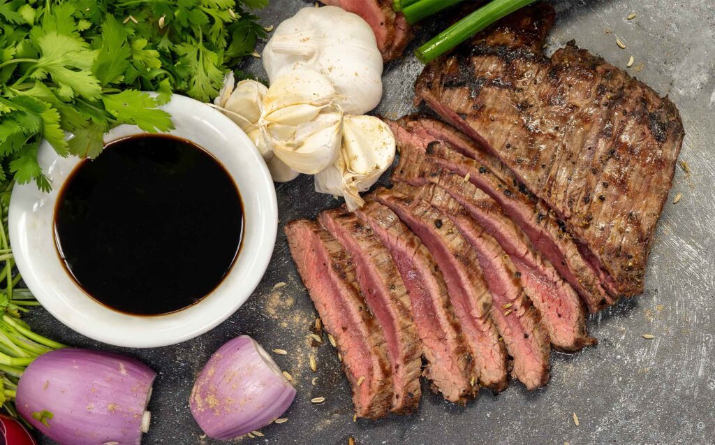 Steak with sauce and garlic and onions on a board