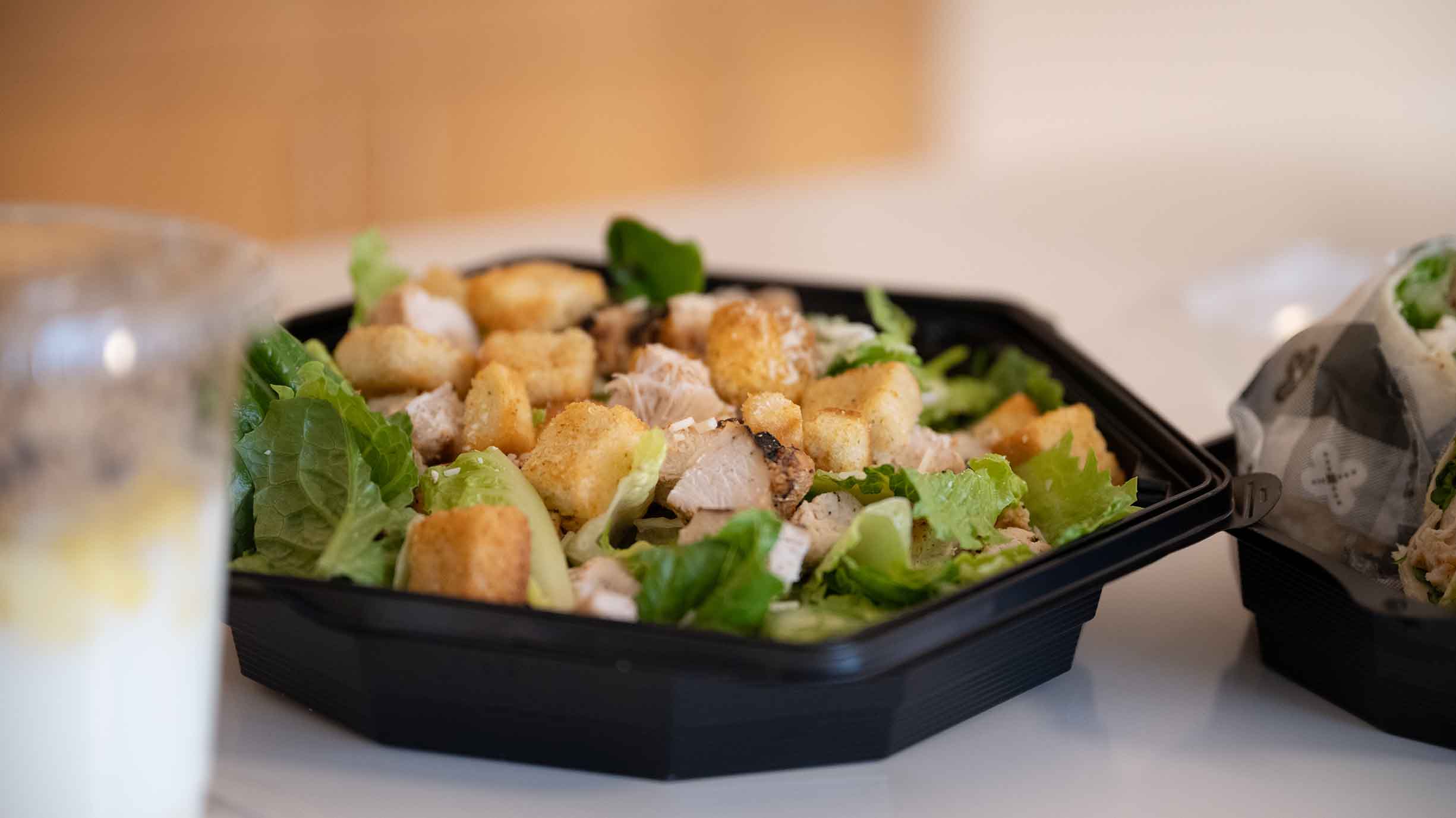 Close up view of a salad and drink in to go containers