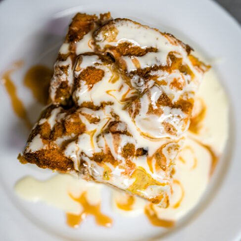 looking down a sweet bar covered with icing and caramel and topped with cinnamon