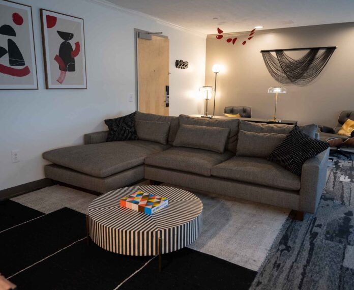 Alumni Queen Suite viewing the living area with couch, stripe coffee table, and lamps.