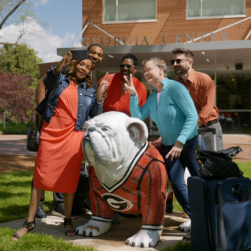 Five hotel guests standing by the bulldog statue in front of the hotel