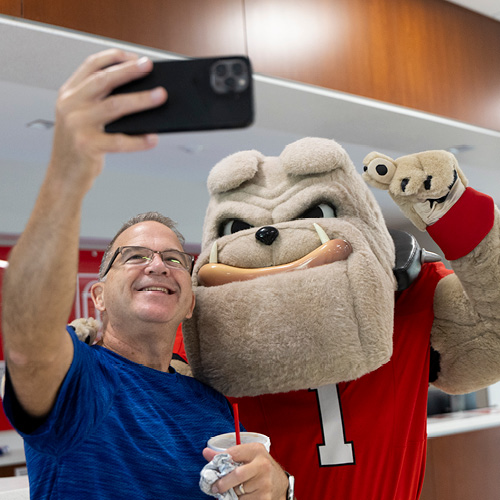 A parent wearing a blue shirt is taking a selfie with Hairy Bulldawg.