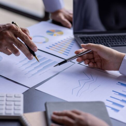 Group of business people point to graphs and charts to analyze market data, balance sheet, account, net profit to plan new sales strategies to increase production capacity.