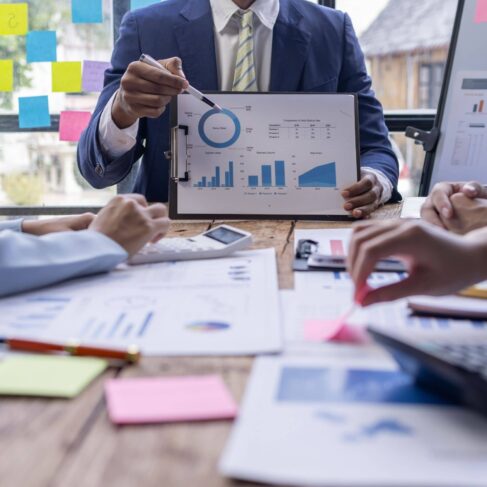 Team businesspeople or an accountant team are analyzing data charts, graphs, and a dashboard on a laptop screen in order to prepare a statistical report and discuss financial data in an office.