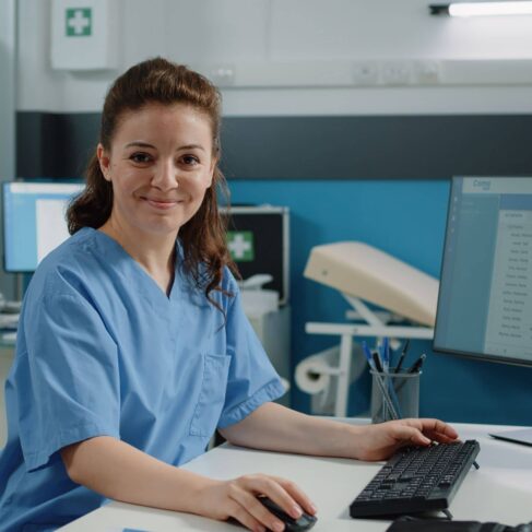 Woman working as medical assistant using technology for healthcare system and examinations at desk.
