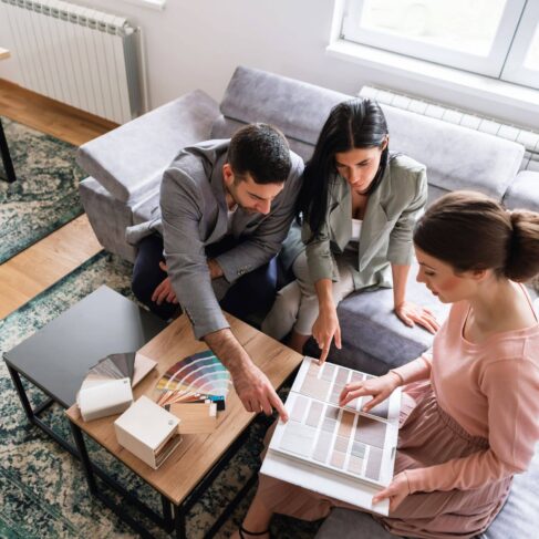 High angle view of a young couple looking at color swatches on a meeting with an interior designer, talking about a home interior.