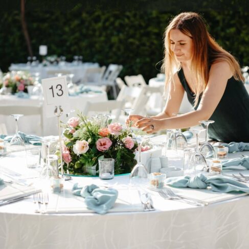 Shot of a woman decorating a table with place card holders in preparation for a wedding reception