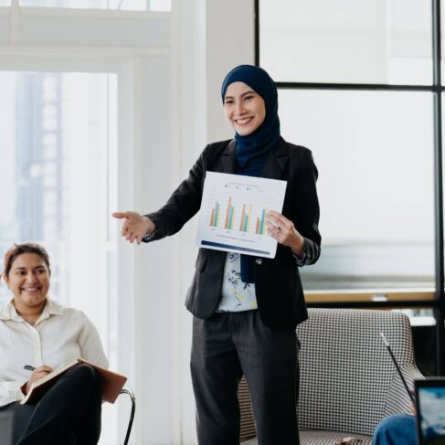A female business entrepreneur holding research data and presenting to her team in office