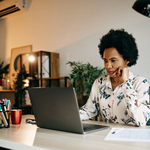 A business woman working from home office at her deck looking at her laptop.