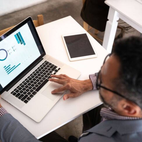 High angle view of a businessman using laptop displaying spreadsheet with graphs and charts in a restaurant.