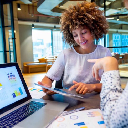 Business colleagues discussing finance charts and graphs on a laptop computer.