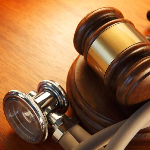 A close up of a gavel surrounded by a stethoscope.