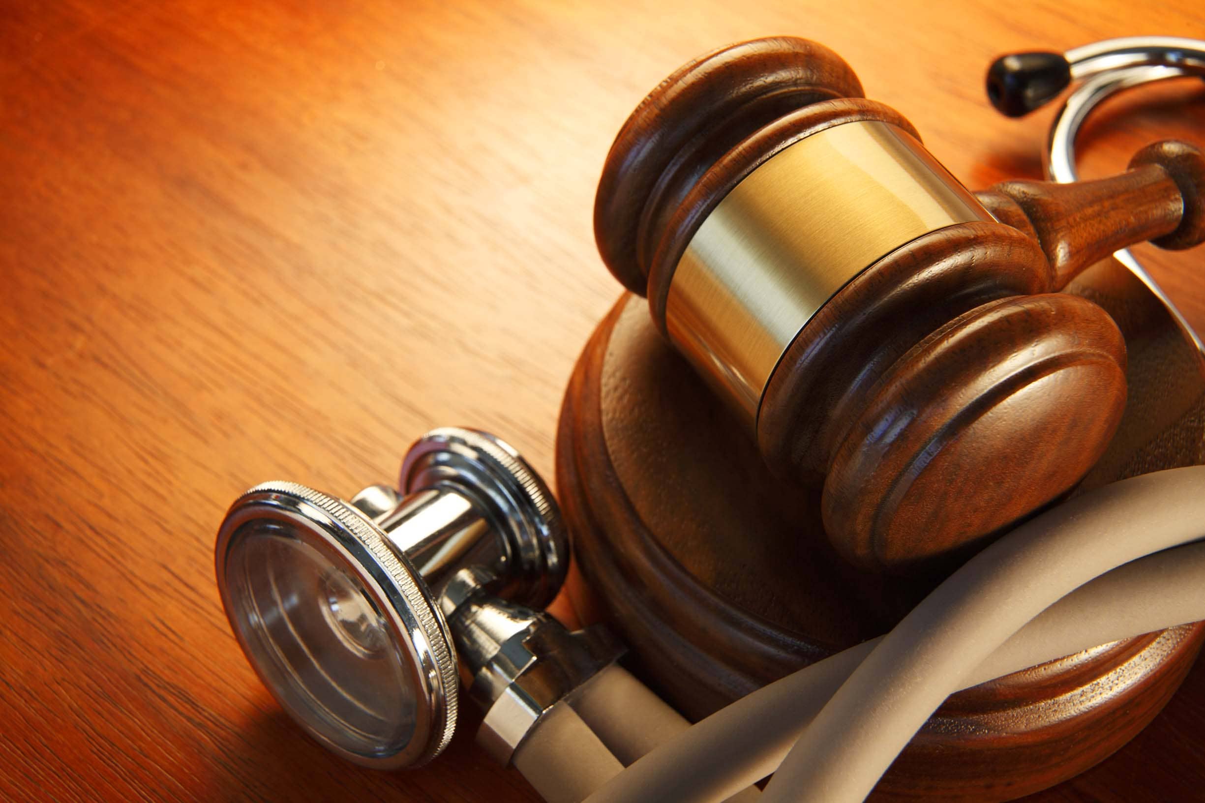 A close up of a gavel surrounded by a stethoscope.