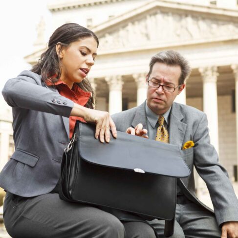 A woman showing a coworker or friend something in her valise.