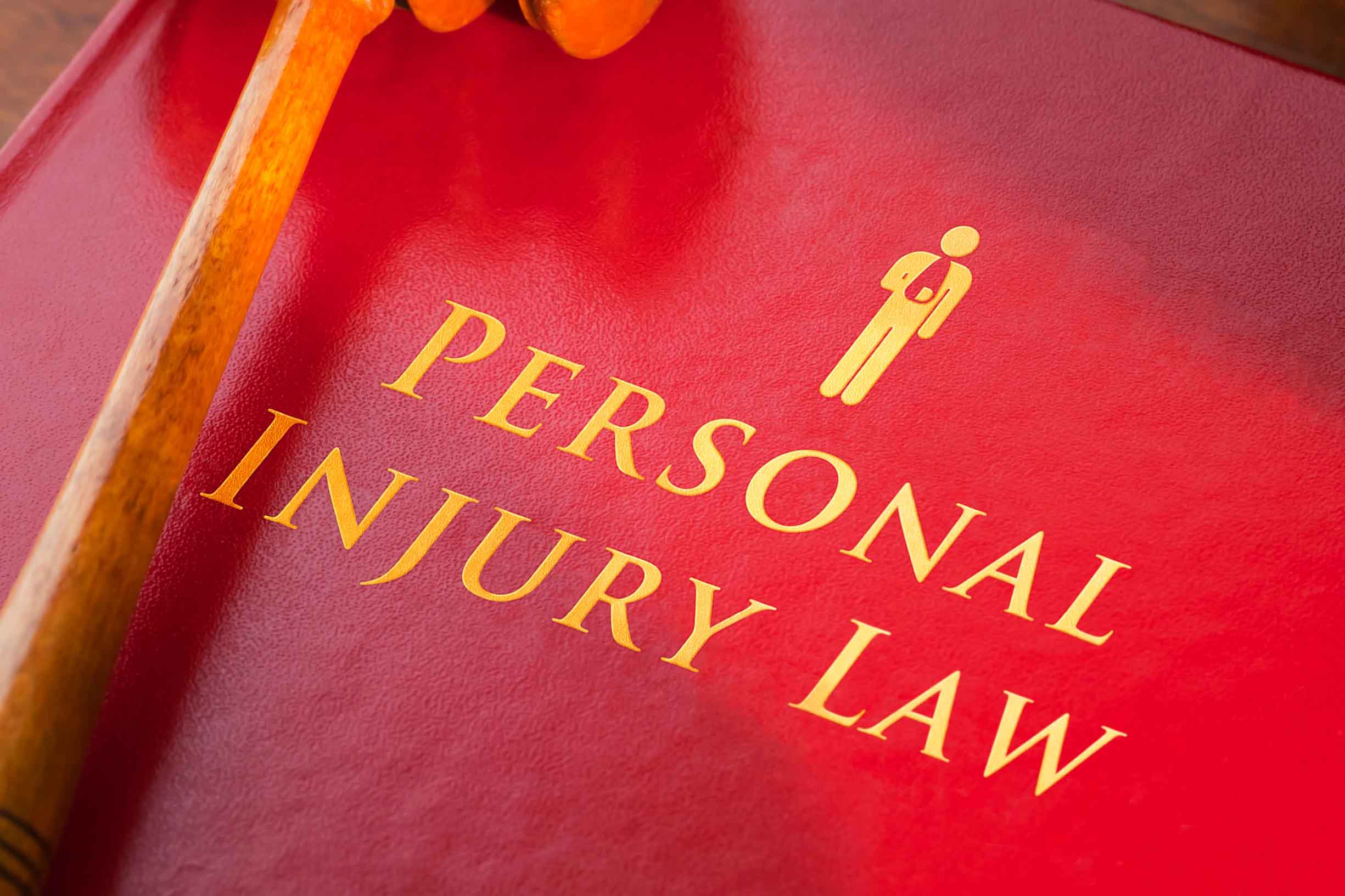 Red leather Personal Injury Law book with with gold embossed type and icon figure with arm in a sling, with a judges gavel.
