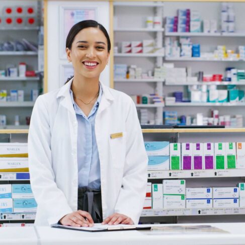 Portrait of a young pharmacist writing notes while working in a pharmacy.