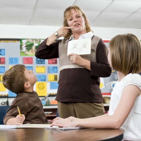Portrait of mid adult teacher with developmental disability with his students in an inclusive classroom.