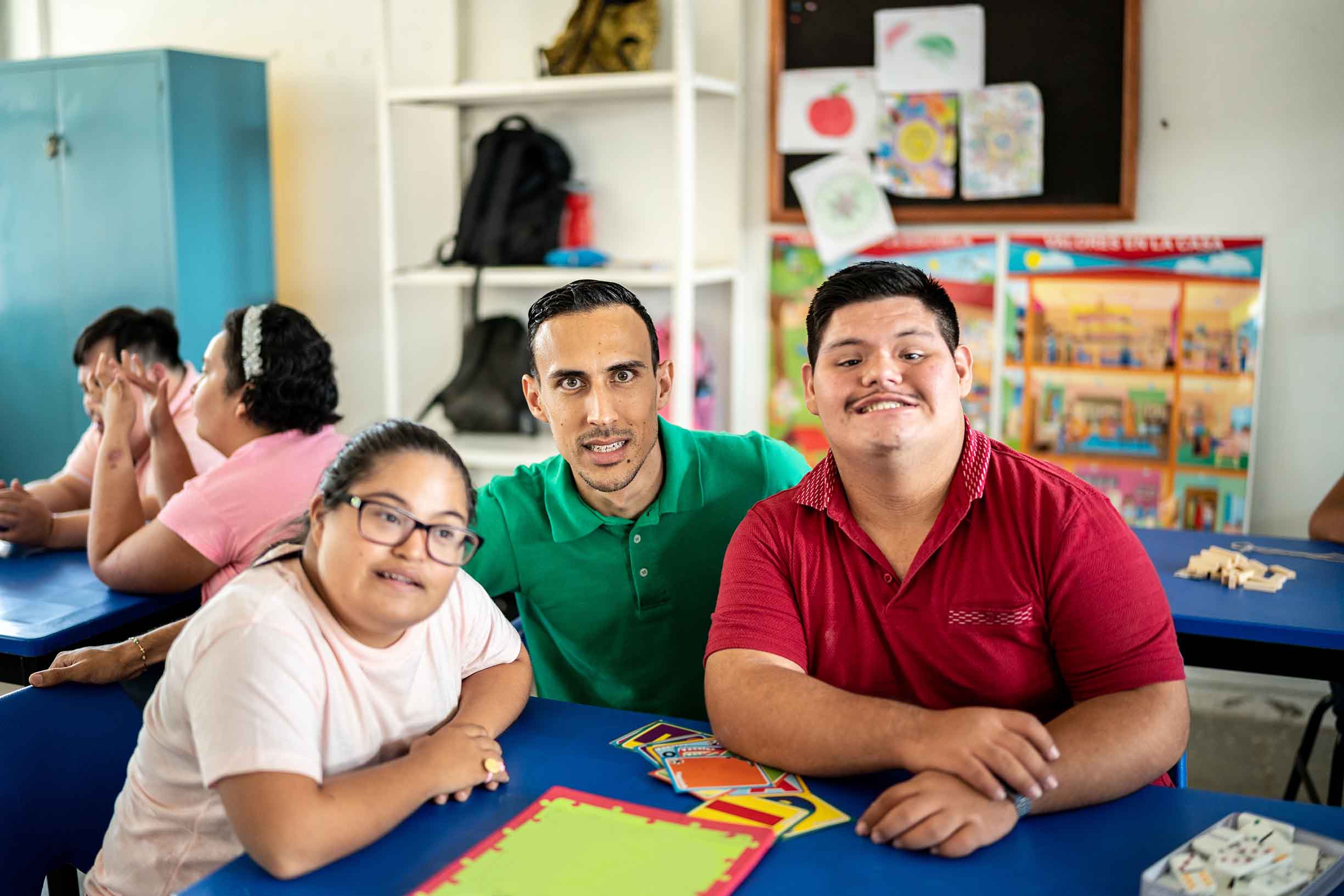 Portrait of mid adult teacher with developmental disability with his students in an inclusive classroom.
