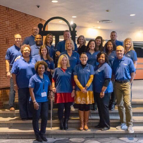 Sherpa students standing in the Georgia Center Pecan Galleria wearing their blue shirts in front of a wooden arch