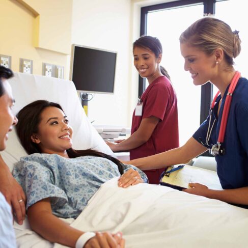 Happy Smiling Medical Team Meeting With Couple In Hospital Room