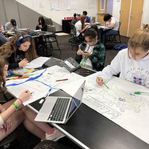 three students sitting at a table with papers