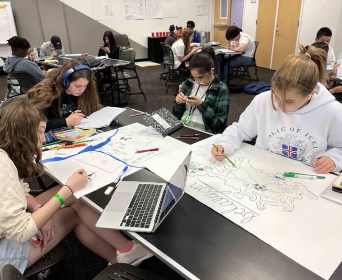 three students sitting at a table with papers