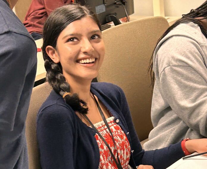 smiling student sitting in front of computer screen