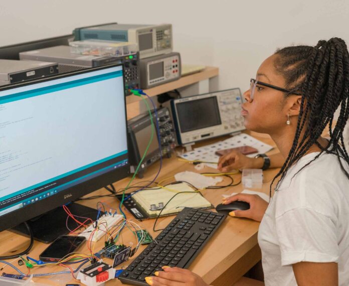 Student sitting in front of a computer looking at code.