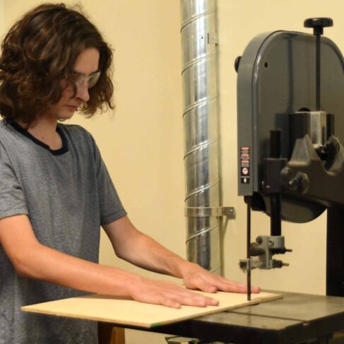 Student using a table saw to cut a piece of wood.