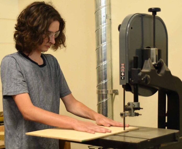 Student using a table saw to cut a piece of wood.