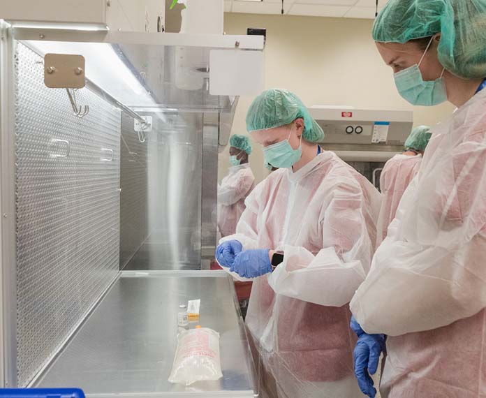 Two students using medical equipment and wearing protective clothing