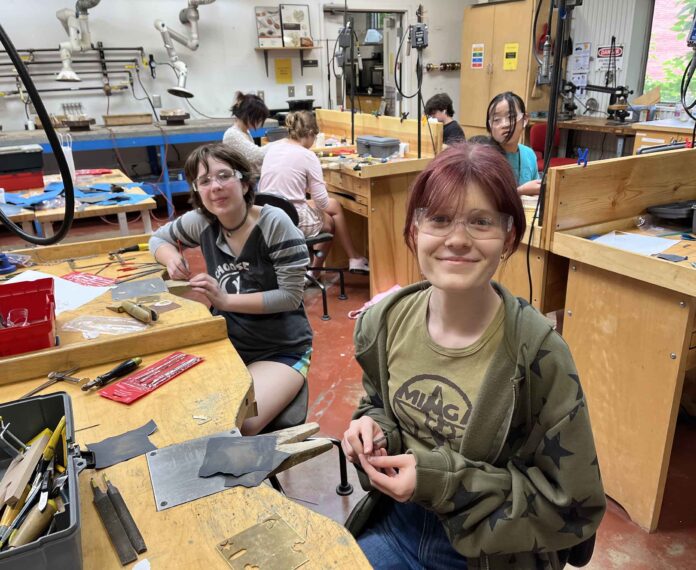 Smiling students at their workstations as they make jewelry