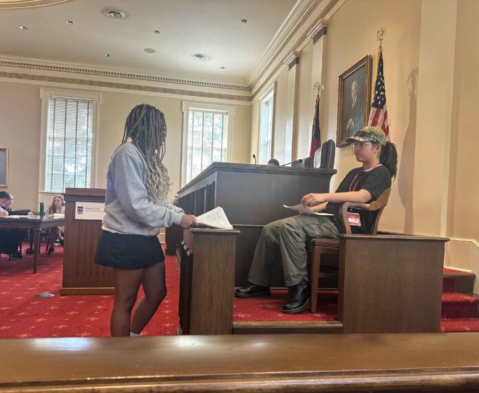 two students in a court room holding papers