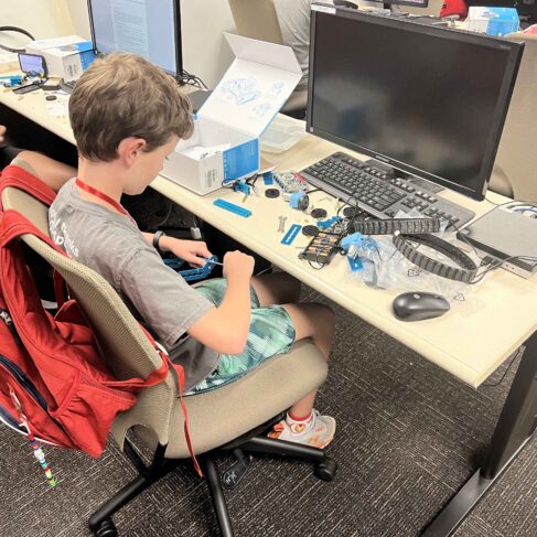 Student building a robot in front of a computer