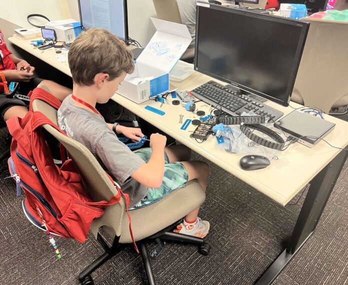 Student building a robot in front of a computer