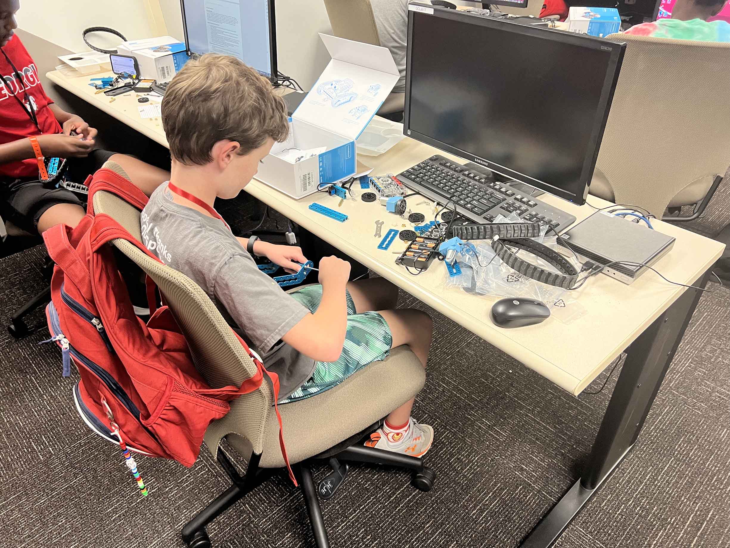 Student building a robot in front of a computer