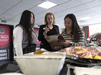 (L-R) Amy Nguyen, Georgia Center student employee trainer Hannah Miller, and Angela Nguyen go over some details for a buffet set up during a conference at the Georgia Center for Continuing Education and Hotel.