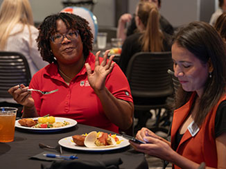 Abony James and Martha Camarillo enjoying the Georgia Center employee event, sitting at a table with food on their plates.