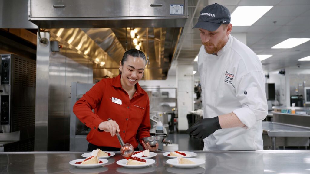 Dustin Ellis showing student worker on preparing strawberry ice cream pie