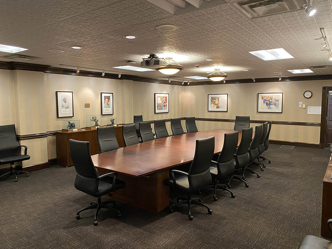 View of the Craige Boardroom with chairs arranged around a table and photos in frames on the walls