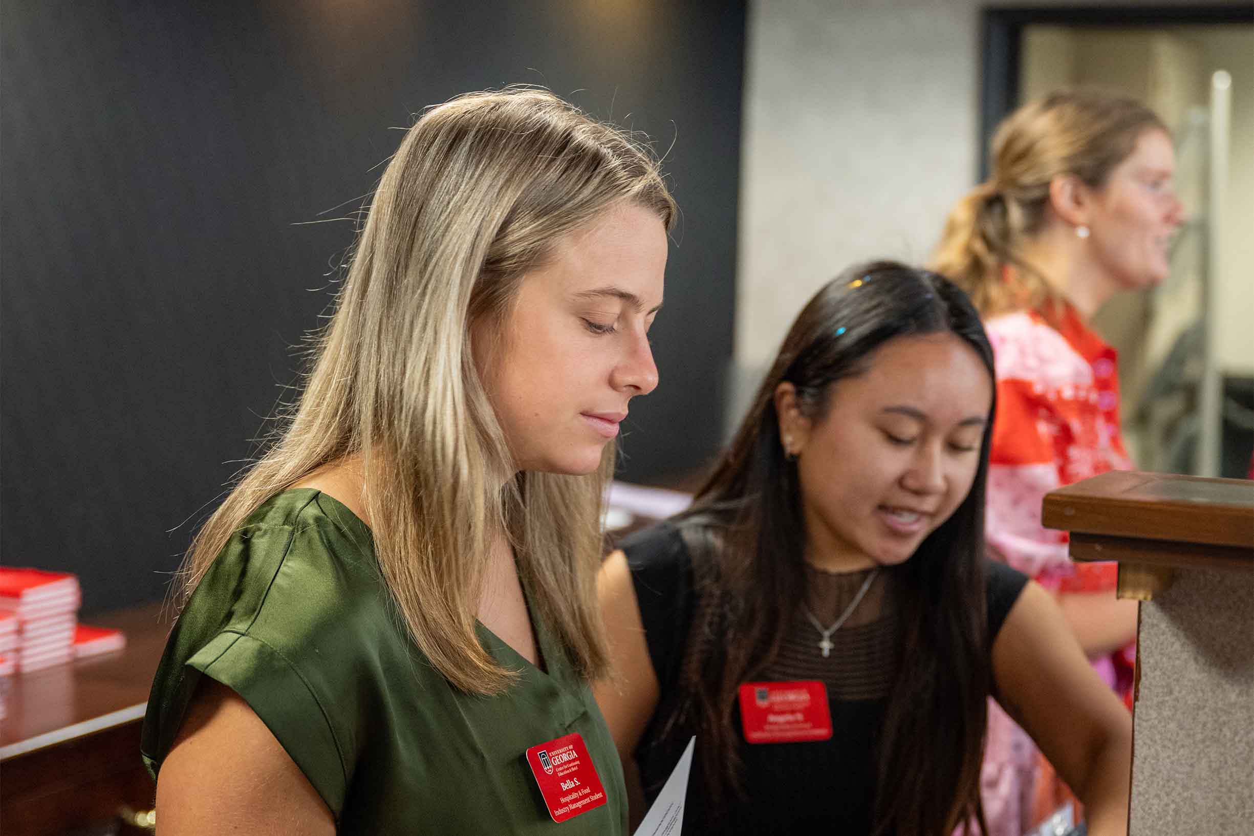 three student workers at the registration desk helping customers