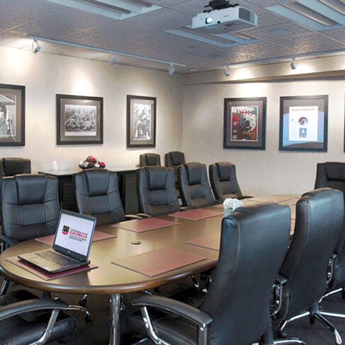 View of the Sanford Boardroom with chairs around the table and photos on the wall and a laptop on the table