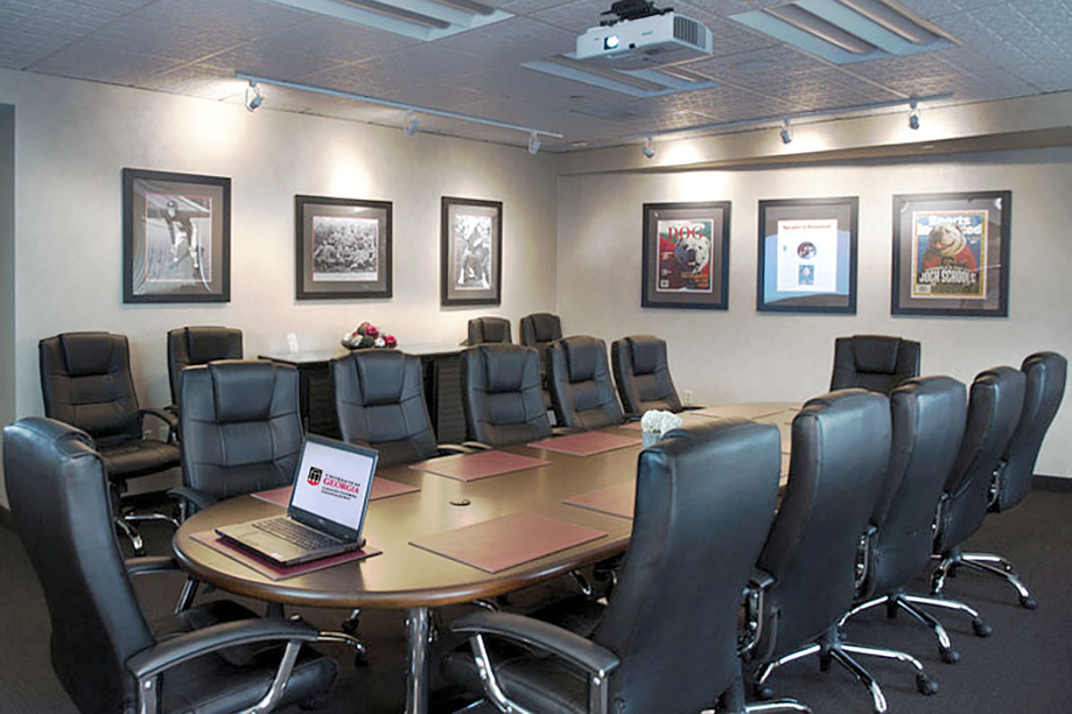 View of the Sanford Boardroom with chairs around the table and photos on the wall and a laptop on the table