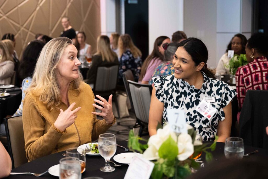two women talking at a table at a conference