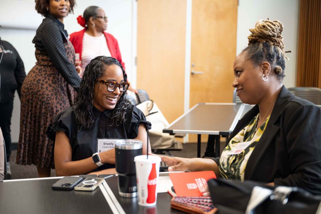 two women in a classroom talking at a conference while sitting in a classroom