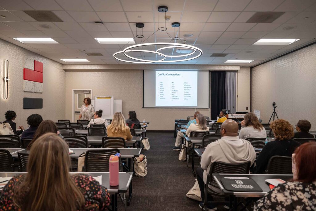 a group of people sitting in a classroom looking at a PowerPoint presentation
