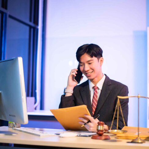 Professional young lawyer at desk with legal scales and gavel, writing documents in office, offering legal services