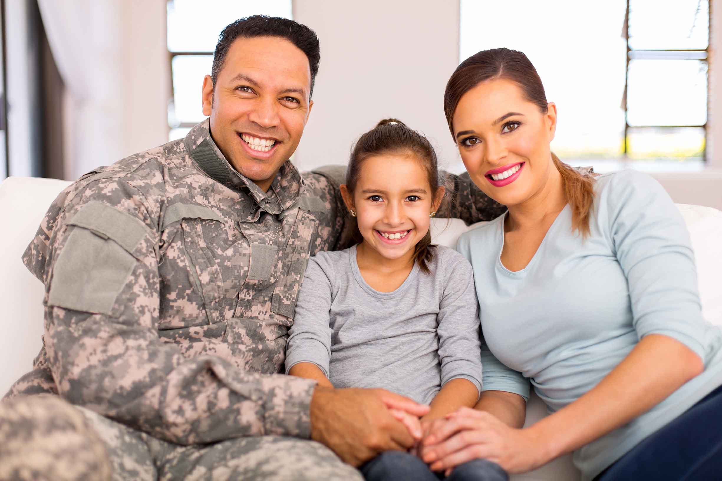lovely young military family sitting on sofa at home