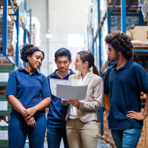 Female manager discussing delivery schedules with staff in warehouse